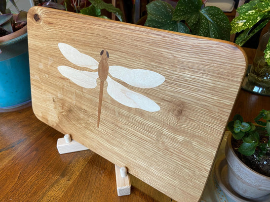 Hand-made art on a wooden canvas.  White Oak charcuterie board; dragonfly inlay of Cherry, Maple and Peruvian Walnut.