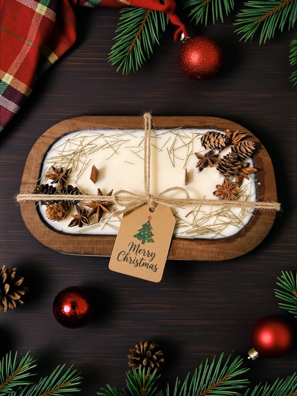 Decorative candle with pine cones and star anise on a wooden tray, surrounded by Christmas decorations.